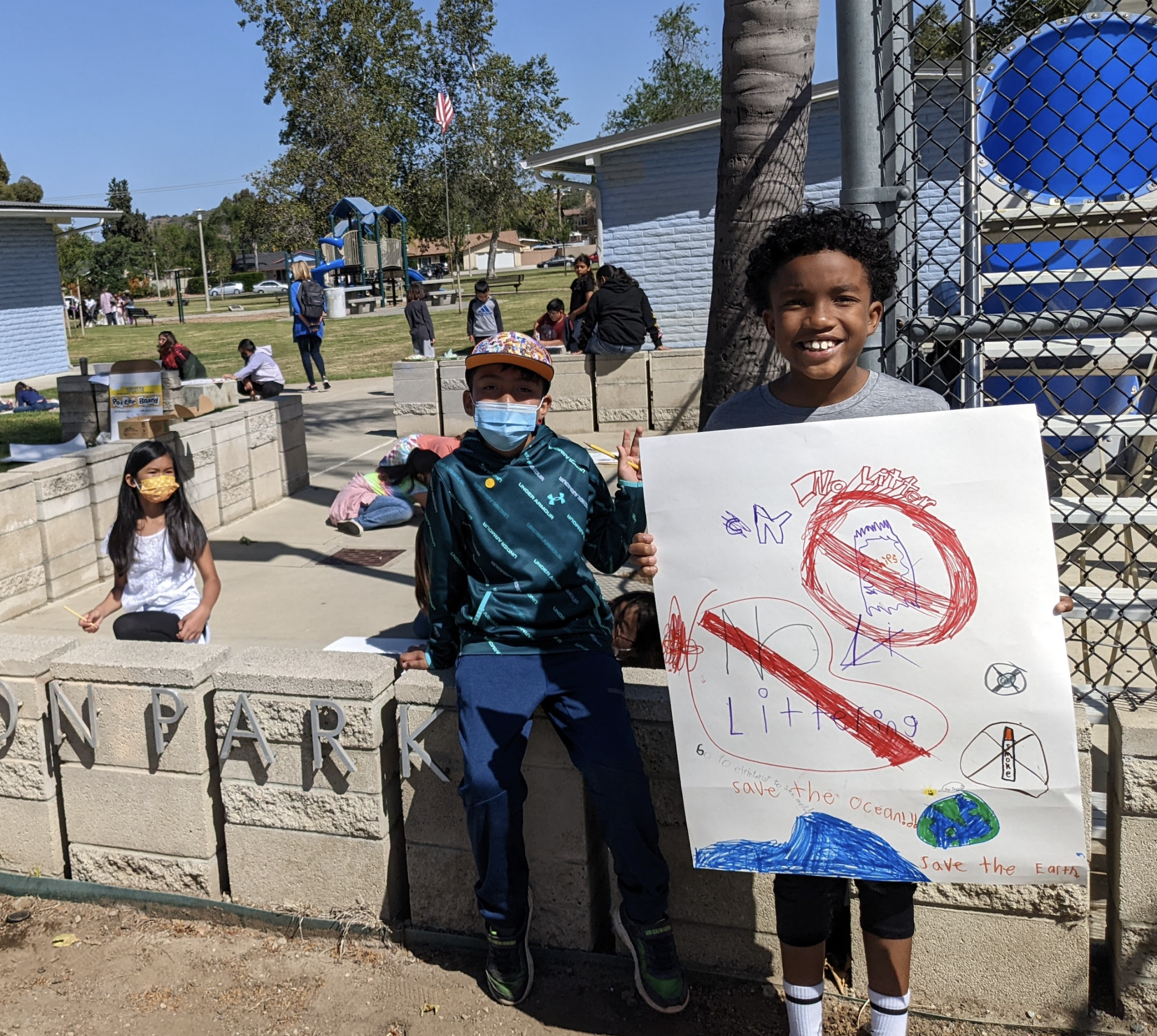 Students pose for the camera with their "don't litter" sign they made for Earth Day.