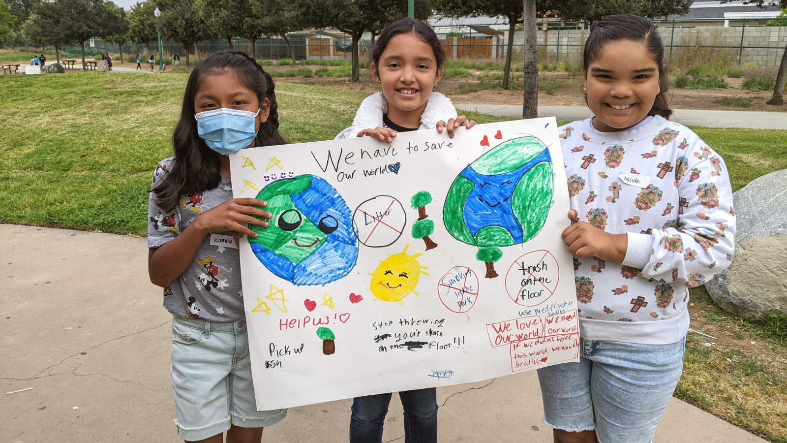 Students hold a sign supporting Earth Day in an Escondido Park.